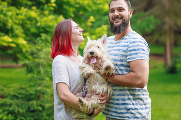 Couple having fun while walking with dog in park