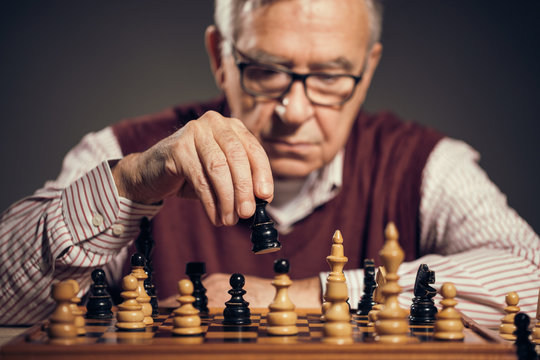 Portrait of senior man who is participating in chess game. 