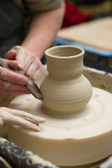 Fototapeta na wymiar Hands of a potter, creating a pot of clay