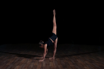Fototapeta na wymiar Girl gymnast doing gymnastic sports exercises on a black background. Sport