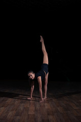 Girl gymnast doing gymnastic sports exercises on a black background. Sport