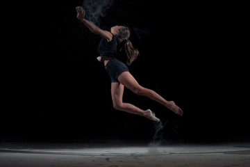 Fototapeta na wymiar Dancing girl in a jump with dust powder