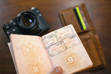 Russian travel passport in hand with wallet and photo camera in the background, travel fees