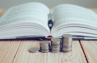 Stack of coin and background book on the table, finance concept.