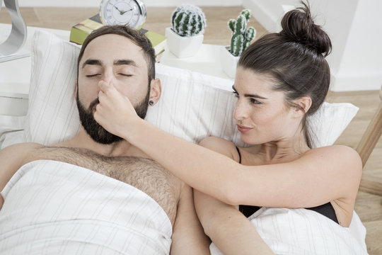 Couple lying in bed with man snoring