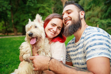 Beautiful couple relaxing in park with their dog