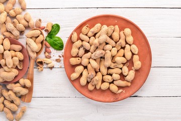 Peanuts on a white wooden background. Healthy snacks. Top view. Free space for text.