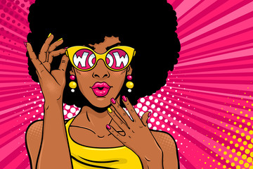 Wow pop art face. Sexy surprised black woman with african hair and open mouth holding sunglasses in her hand with inscription wow in reflection. Vector bright background in pop art retro comic style. - obrazy, fototapety, plakaty