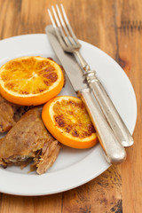 baked duck with orang on white dish with fork and knife