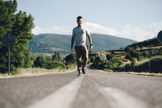 Young man looking at the camera in the middle of the road surrounded by nature in the countryside in Madrid, Spain