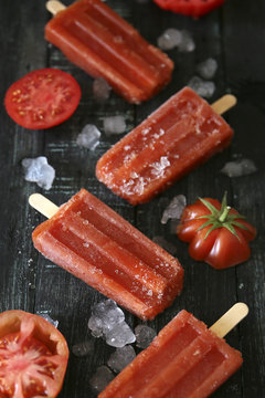 Tomato ice lollies on black wood