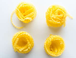 vivid yellow fettuccine pasta on white plate on white background with shadow