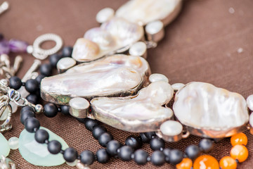Biwa pearl necklace laying on natural brown linen tablecloth. Black onyx and agate gemstones around.Healing, powerful energy for crystal therapy treatments. Esoteric background