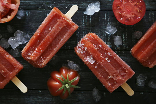 Tomato ice lollies on black wood