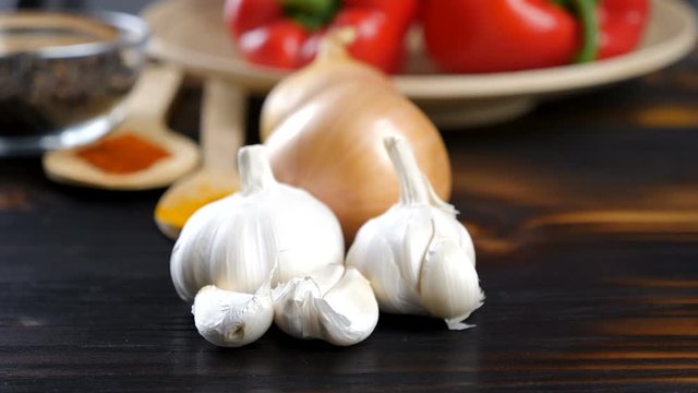 Parallax dolly footage of garlic in front of other vegetables on wooden background