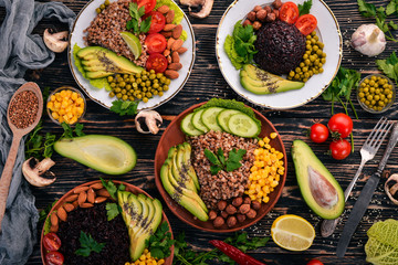 Healthy food. Black rice, buckwheat, avocado, cherry tomatoes, green peas and hazelnut. On a wooden background. Top view. Free space for your text.