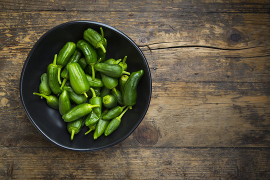 Bowl of Pimientos de Padron on dark wood