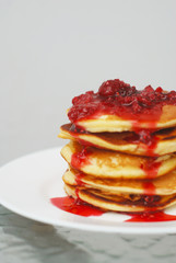 A Stack of Pancakes with Strawberry Jam isolated on white plate and gray Background.