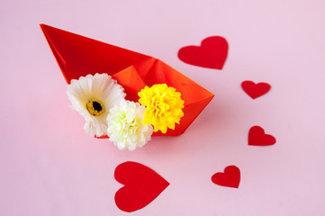 On a pink background an orange ship with flowers and red hearts