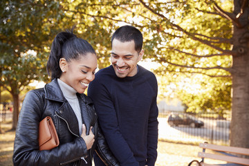 Young Hispanic couple walking hand in hand in Brooklyn park