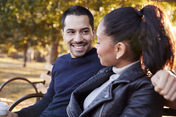 Young couple sitting on bench in Brooklyn park, close up
