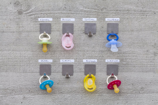 Pacifiers hanging on concrete wall with name tags