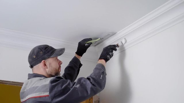 Close up shot of a experienced worker painting celling plinth