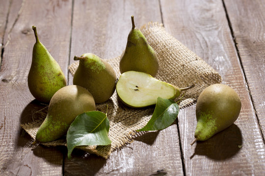 Whole and sliced pears and leaves on jute and wood