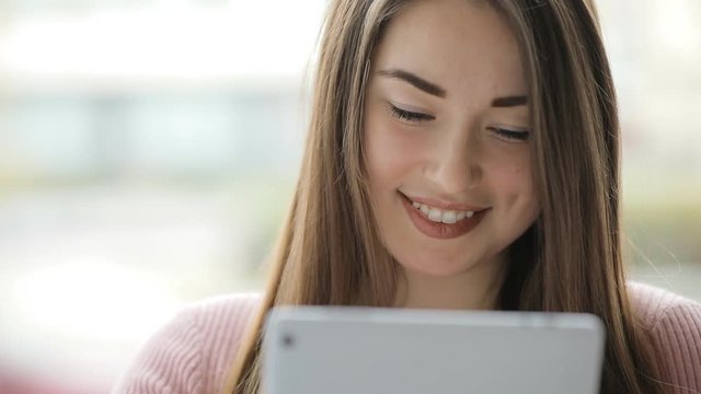 Young european woman using tablet pc touchscreen at window