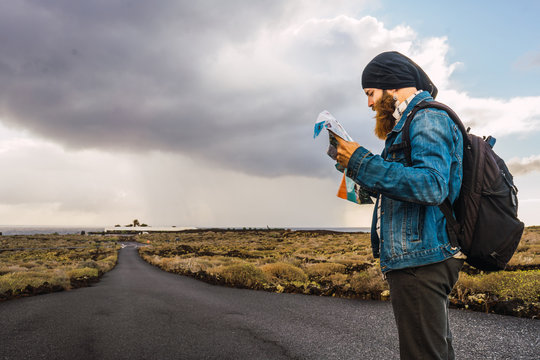 Side view of man reading map while standing on road