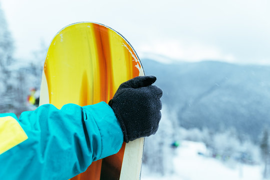 man stands with snowboard on the top of the hill