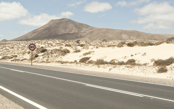 Spain, Fuerteventura, Corralejo, Parque Natural de Corralejo, view of empty road and road sign