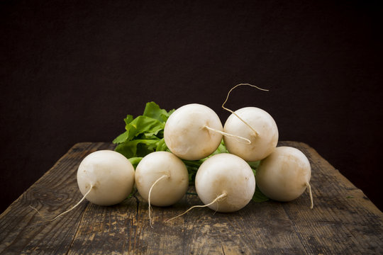 Turnips on dark wood in front of black background