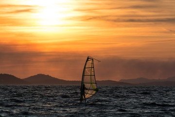 Sunset over the sea or ocean and extreme freestyle sport windsurfing