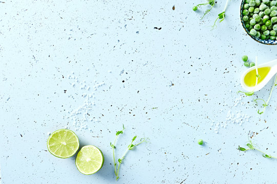 Symbolic food background with lime, olive oil, frozen peas and pea sprouts