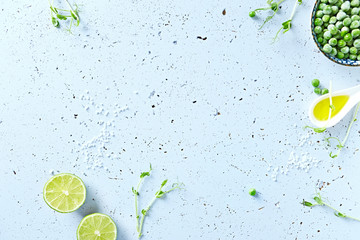Symbolic food background with lime, olive oil, frozen peas and pea sprouts