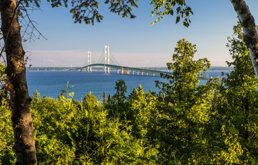 Summer Vacation At Mackinaw. View of the Mackinac Bridge framed by the lush green forest of the Upper Peninsula with the blue waters of Mackinaw at the horizon. St. Ignace, Michigan.