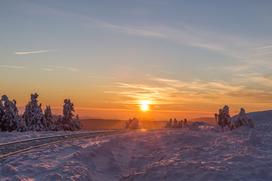 Germany, Saxony-Anhalt, Harz National Park, Brocken, rail tracks of Harz Narrow Gauge Railway in winter against the evening sun