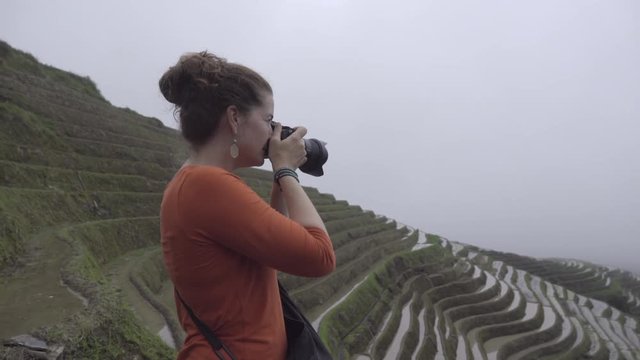 Pan to a woman tourist near rice paddy in China