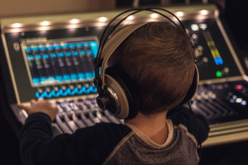 Small DJ with headphones in recording studio.