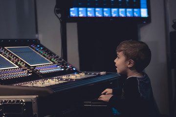 Little composer editing music on audio mixer in music studio. - obrazy, fototapety, plakaty
