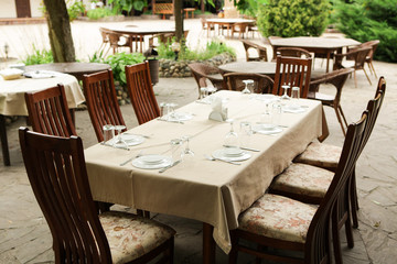 Fototapeta na wymiar Street restaurant in the summer. Wooden chairs and table served with dishes