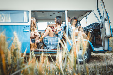 Happy friends driving a vintage minivan