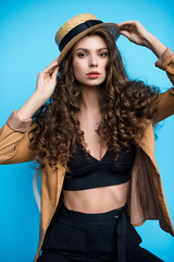 Naklejka premium beautiful young woman with long curly hair in fashionable canotier hat and jacket