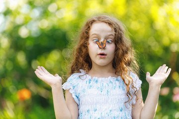 Surprised girl with a butterfly on her nose, focus on a girl face.