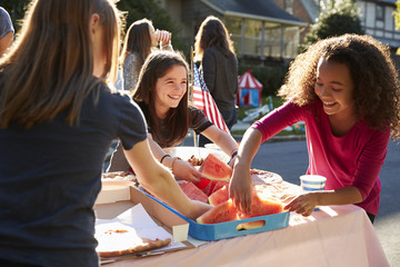 Girls serving themselves watermelon at a block party