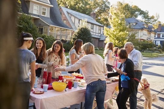 Neighbours Talk Standing Around A Table At A Block Party