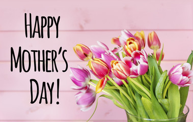 Happy Mother's Day Text with  Tulips on Pink Rustic Wooden Background. Greeting Card Concept. 