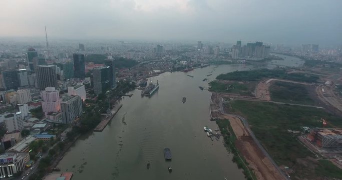 HO CHI MINH CITY, VIETNAM – MAY, 2016 : Aerial shot over Saigon river at sunset with Ho Chi Minh cityscape and boats in view