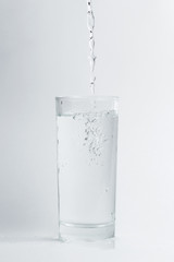 Pouring clear water into glass. Isolated on white background. Glass of  mineral water